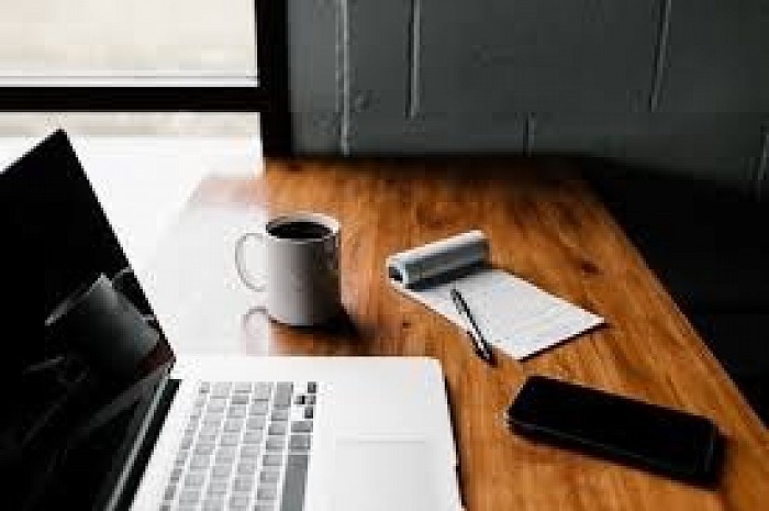 A laptop and documents on an unoccupied desk.